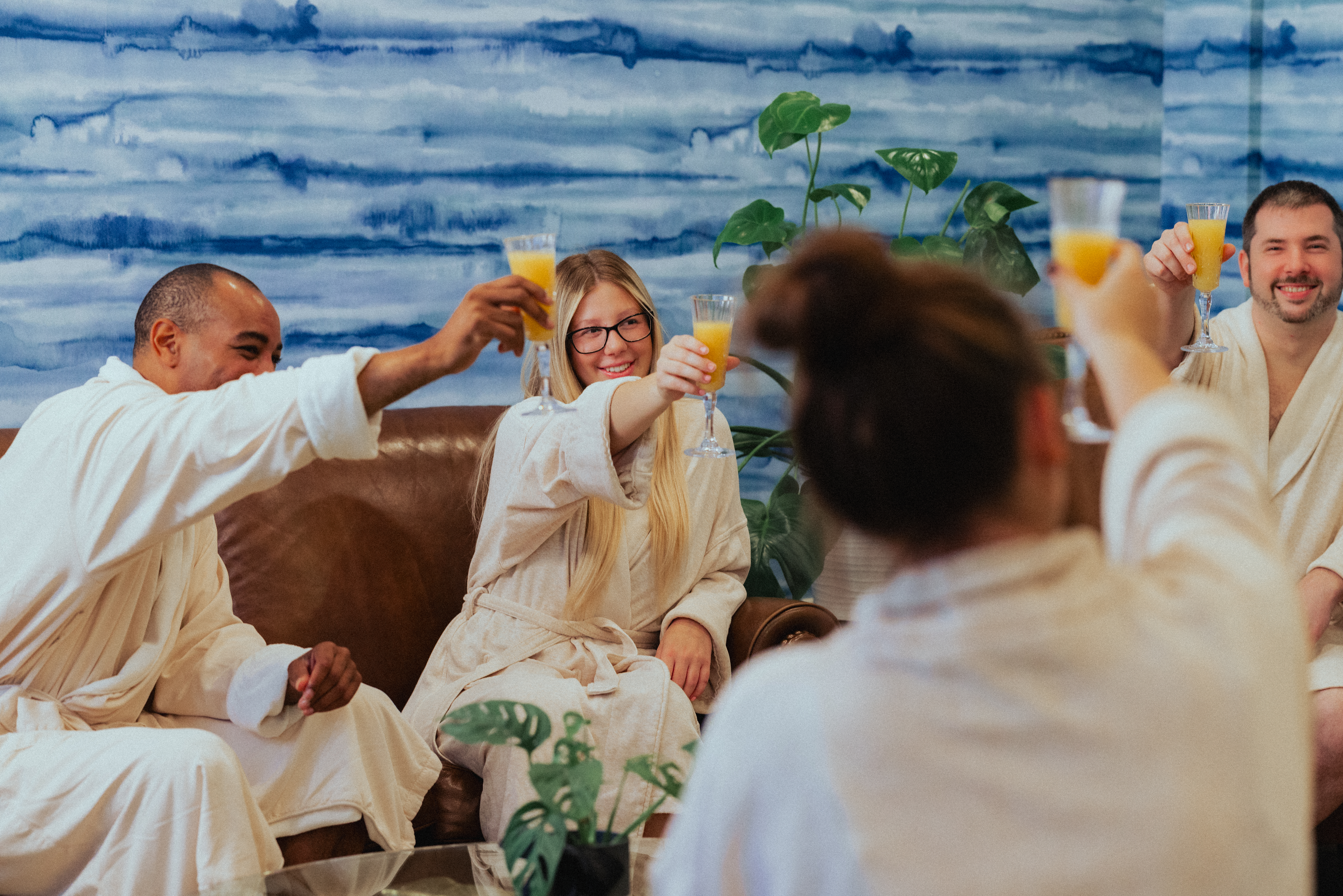 Guests in robes raising glasses together inside the Spa Sanctuary at The Lodge Spa at Tailwater Lodge.